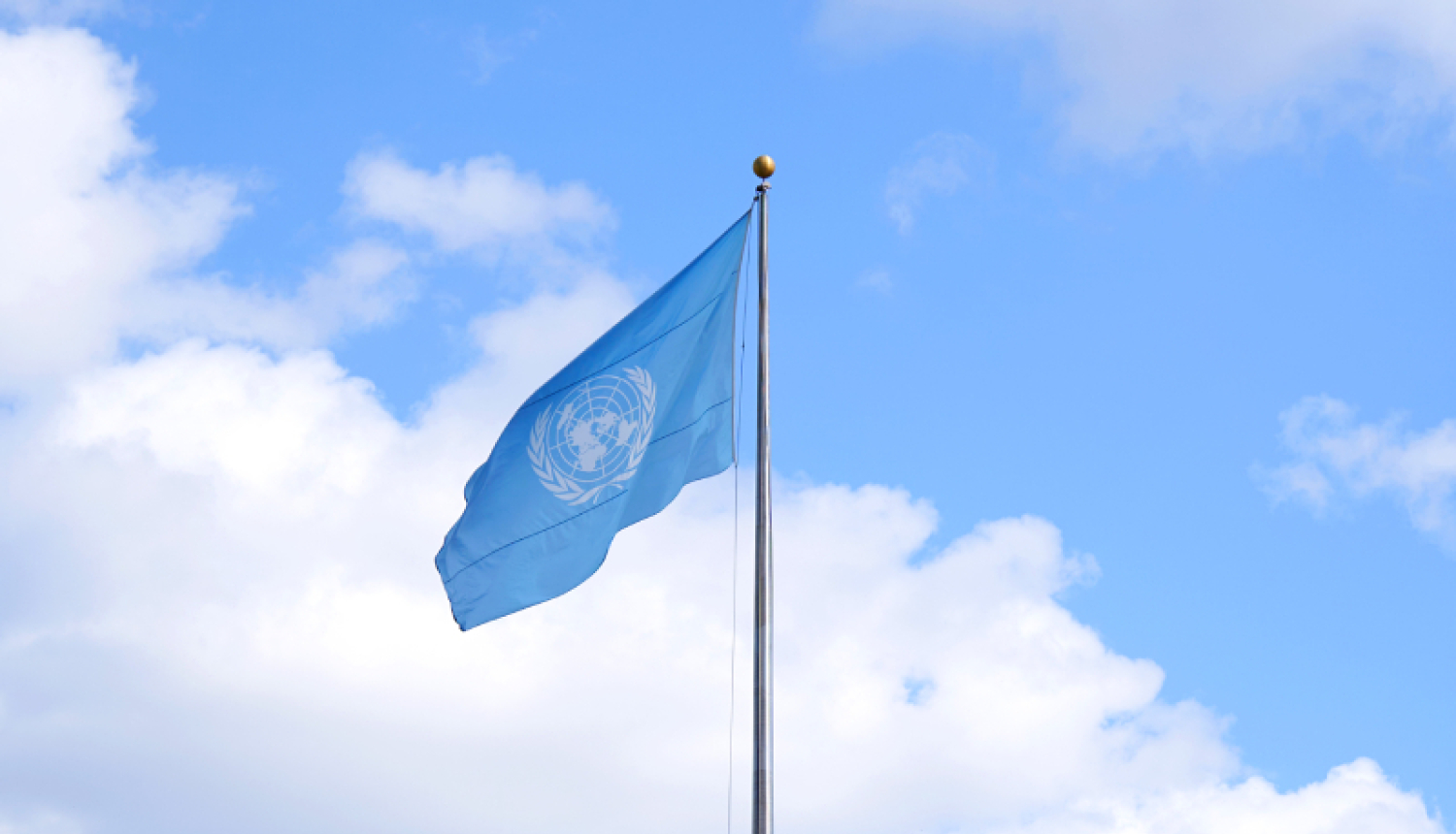 The UN flag flutters in the blue sky
