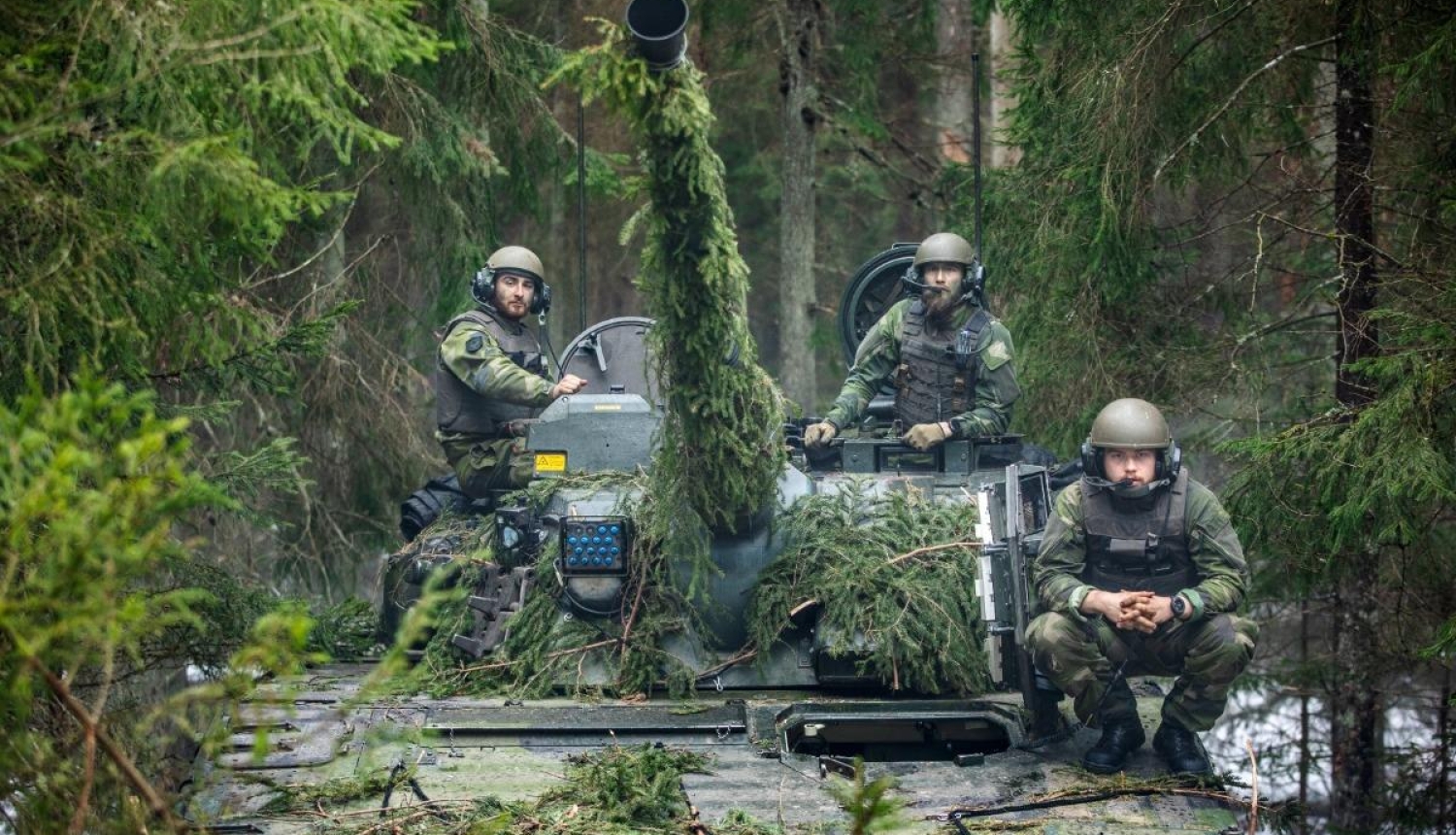 Nomaskējušies NATO daudznacionālās kaujas brigādes vīri un tanks mežā