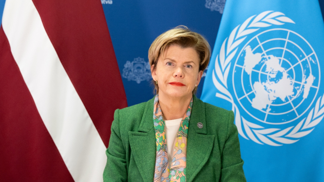 Baiba Braže saka uzrunu, viņai aiz muguras Latvijas un ANO karogi