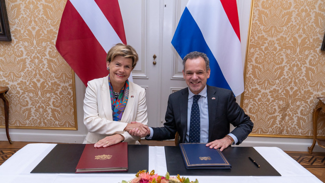 Baiba Braže un Caspar Veldkamp spiež rokas pēc līguma parakstīšanas