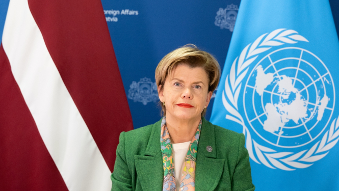 Baiba Braže saka uzrunu, viņai aiz muguras Latvijas un ANO karogi