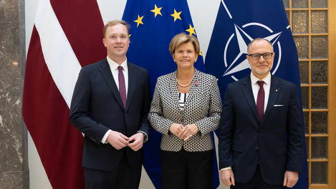 Ekonomikas ministrs Viktors Valainis, ārlietu ministre Baiba Braže un aizsardzības ministrs Andris Sprūds uz Latvijas, ES un NATO karogu fona