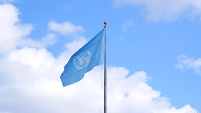 The UN flag flutters in the blue sky
