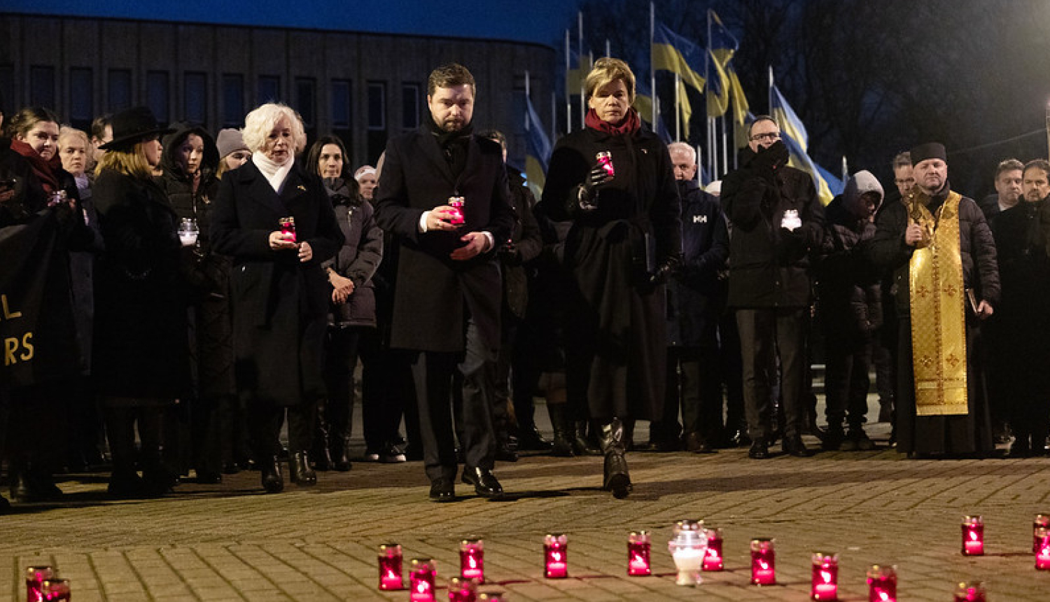 Pasākuma dalībnieki noliek svecītes