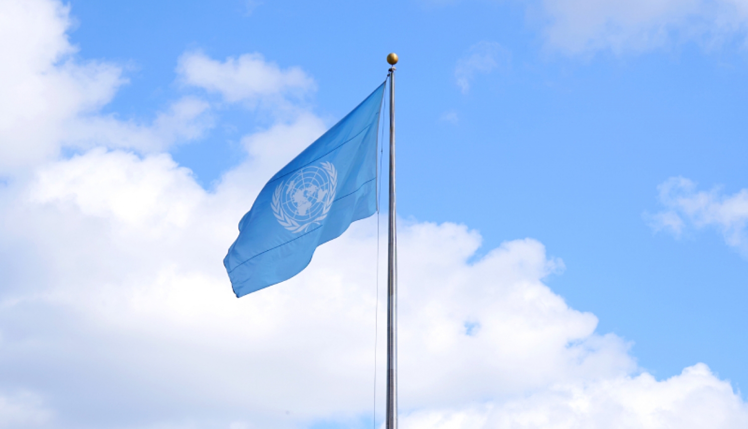 The UN flag flutters in the blue sky